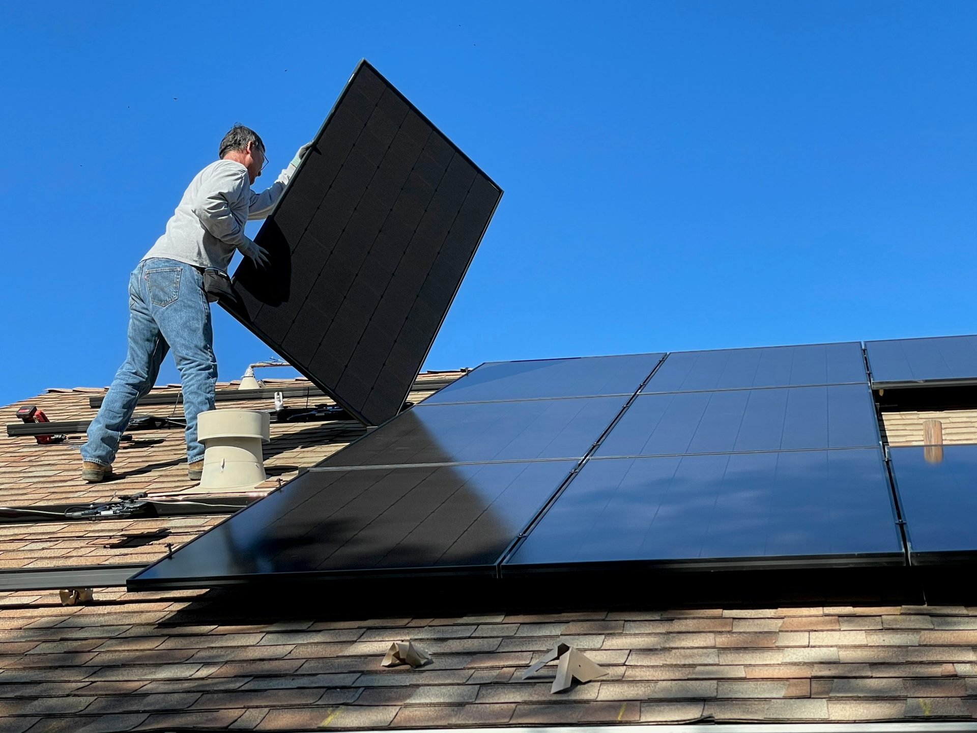 man in white dress shirt and blue denim jeans sitting on white and black solar panel